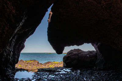 Rock formation on beach against sky