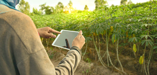 Midsection of man using mobile phone on field