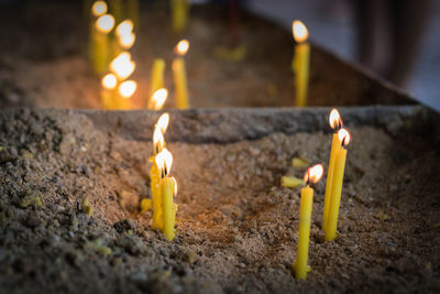 Close-up of lit candles in sand at church