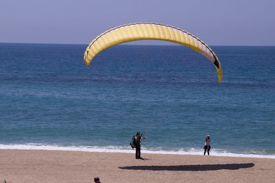 People on beach by sea against sky