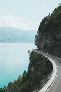 Scenic view of sea by mountain against sky