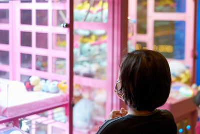 Rear view of kid standing in picker game arcade