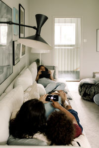 Family using wireless technologies while lying on sofa at home