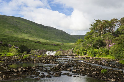 Scenic view of river by mountains against sky