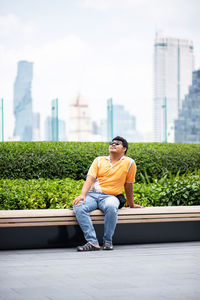 Smiling man looking up while sitting in garden