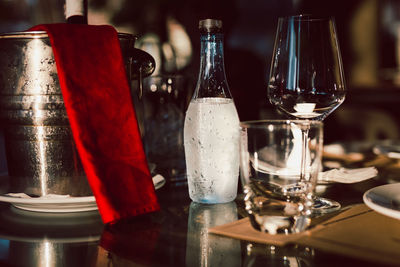 Still life of empty wine glasses and bottle of mineral water on table.