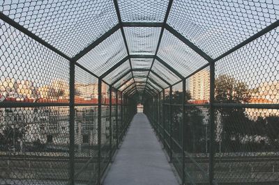 Bridge against sky seen through chainlink fence