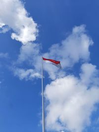 Indonesian flag against blue sky and white clouds in low angle view on a sunny day