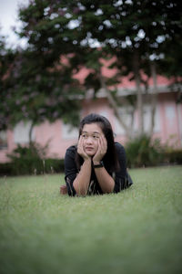 Woman looking away while leaning on elbows over grass