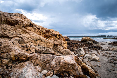 Rock formation on beach against sky