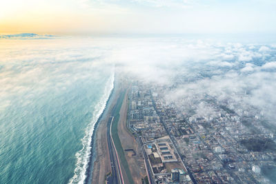 Aerial view of city by sea against sky