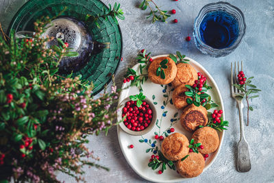 Breakfast set. russian cheese cakes on a craft ceramic plate with lingonberry over a blue background