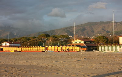 Scenic view of beach by buildings against sky