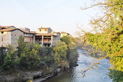 River amidst houses and trees against sky