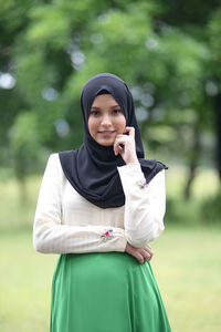 Smiling young woman standing against blurred background