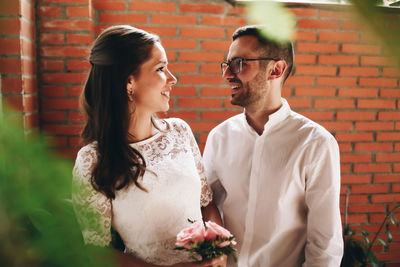 Close-up of couple standing by brick wall