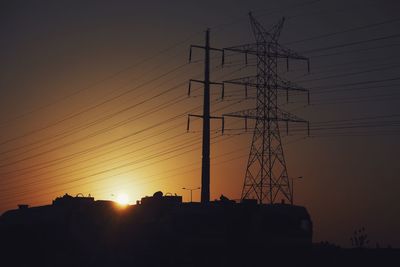 Low angle view of silhouette electricity pylon against sky during sunset