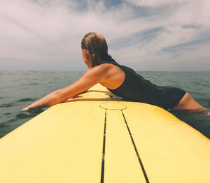 Woman sitting on boat in sea against sky