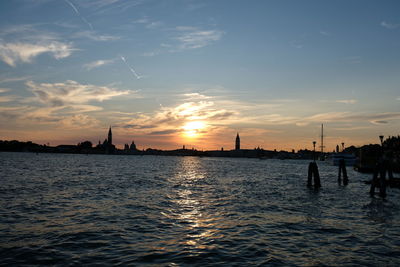 Silhouette of city at waterfront during sunset