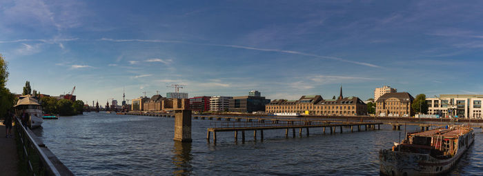 Bridge over river by buildings in city against sky