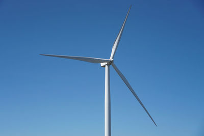 Low angle view of wind turbine against clear blue sky