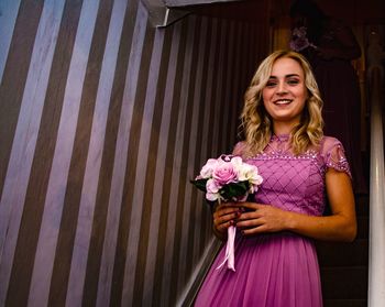 Portrait of a smiling young woman standing against blue wall
