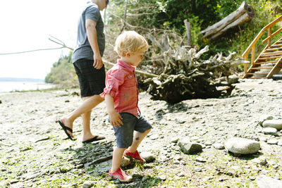 Side view of a father and son walking on a rocky beach on a sunny day