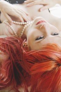 High angle view of redhead woman lying with pearl necklace