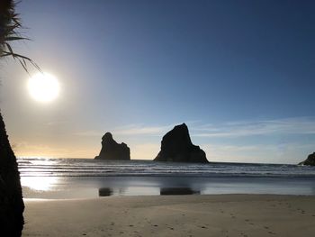 Silhouette rocks on beach against sky during sunset