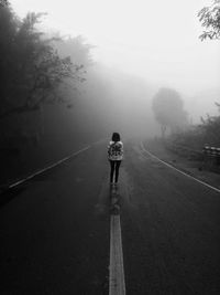 Rear view of man walking on road