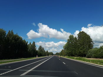 Road by trees against sky