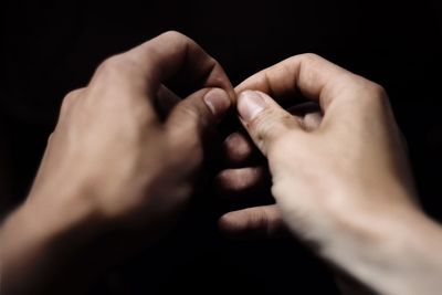 Cropped image of hands gesturing against black background