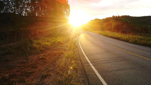 Empty road along countryside landscape at sunset