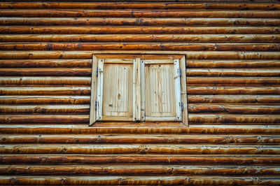 Closed window amidst wooden wall