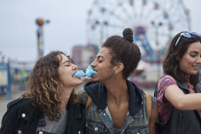 Friends eating cotton candy at an amusement park