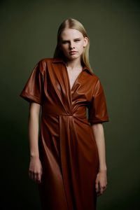 Portrait of young woman standing against wall