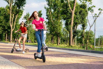 Cheerful women using push scooter