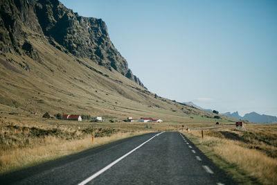 Road by mountains against clear sky