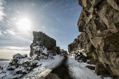 Empty walkway amidst rock formations during winter on sunny day