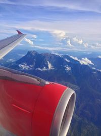 Airplane flying over mountains against sky