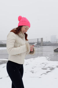 Woman wearing hat standing against snow during winter