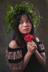 Portrait of a beautiful young woman holding red flower