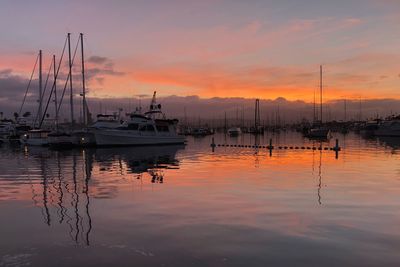 Sailboats moored on sea against sky during sunset