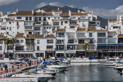 Boats in harbor by buildings in city