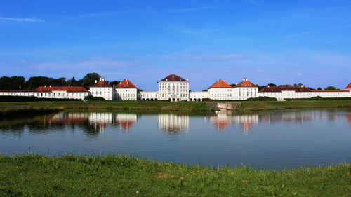 Reflection of buildings in lake against blue sky