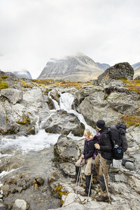 Couple in mountains looking at stream