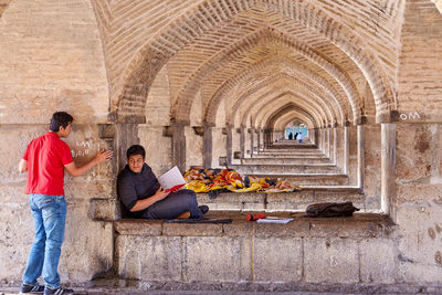 People sitting in corridor of historic building