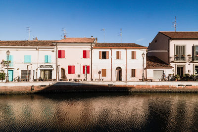 Houses by river against sky in city