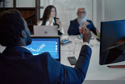 Rear view of man using laptop at office