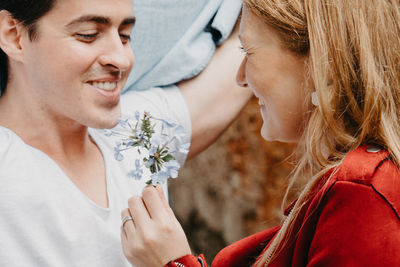 Close-up of smiling woman holding flowers by man